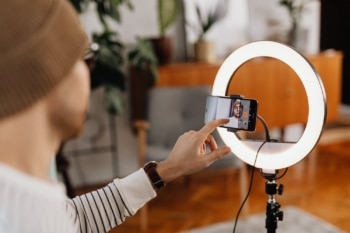 A person learning how to become a UGC Creator by filming content with a smartphone and ring light.