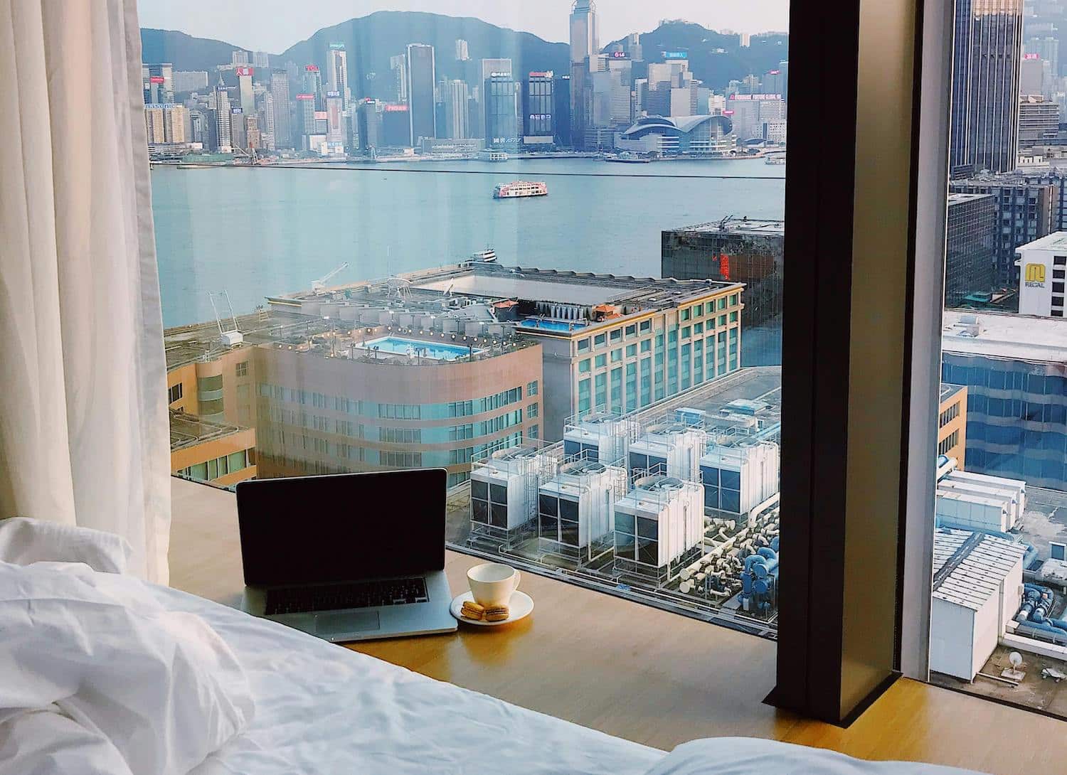 A laptop in a hotel room overlooking a city.