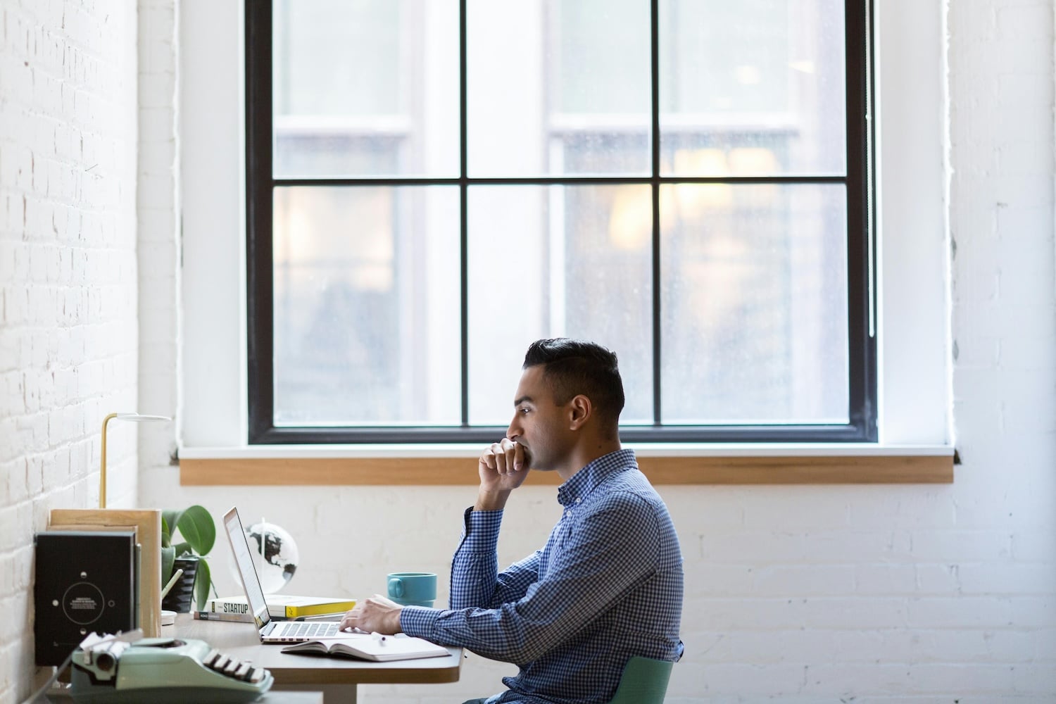 A man on his computer, researching how to start a newsletter for free.