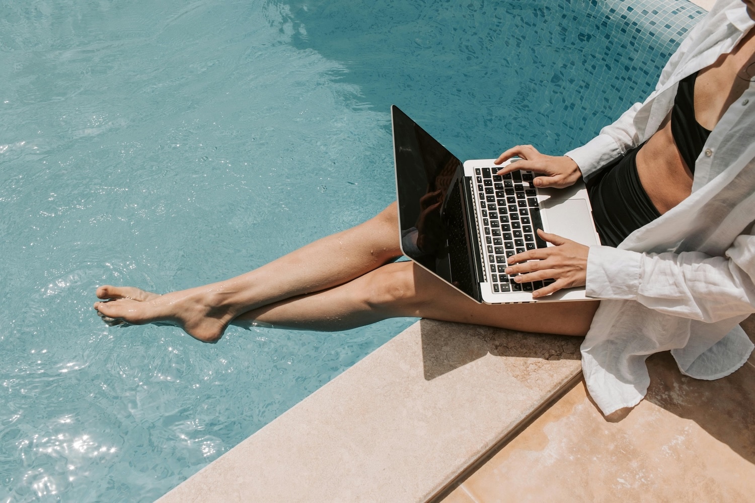 A woman catching up on her favorite newsletter while sitting by the pool.