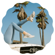 Woman with her legs up towards the sky next to the palm trees